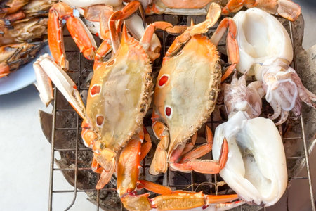 Grilled seafood on open street market, showcasing fresh crabs and squidの写真素材