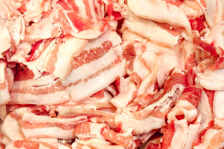 Backdrop of thinly sliced bacon strips arranged in heap, showcasing intricate marbling of fat and...
