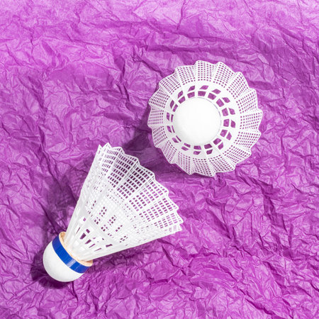 Sport composition with two badminton shuttlecocks on crumpled purple paper, combining healthy sports with playful creativity. Concept of active lifestyle and casual sports. Square formatの写真素材