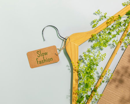 Slow fashion. Wooden hanger with tag with text Slow fashion with tree branch. Perfect visual for organic branding, sustainability concepts, slow fashion, or conscious lifestyle themesの写真素材