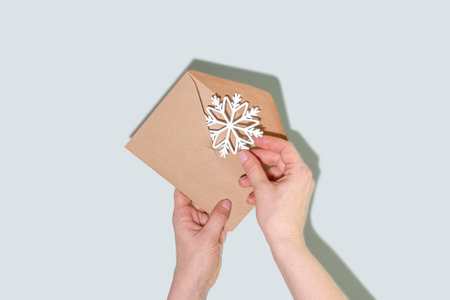Kraft Envelope With White Snowflake Decoration In Hands On Blue Backgroundの写真素材