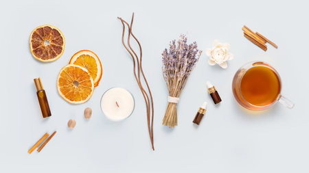 Relax at home. Cup of herbal tea, aroma candle, sticks, lavender flowers, dry orange slices and natural oils on a blue background. Self care and me time conceptの写真素材