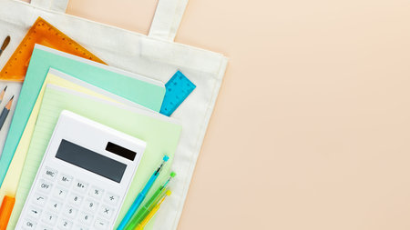 Back to school flat lay with multicolored notebooks, pens, rulers and calculator on a white textile...