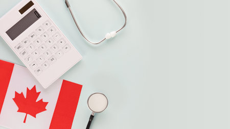 Medical insurance in Canada. Calculator, stethoscope, flag of Canada on a blue background with place for text. Banner of treatment and medical care in Canadaの写真素材