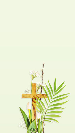 Christian cross with palm leaf, and spring flowers on soft green backgroundの写真素材