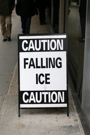 sign on a sidewalk in downtown Chicago warning people to watch for falling ice from the building aboveの写真素材