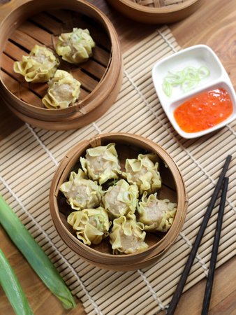 Siomay ayam, steamed dumpling dimsum with the main ingredients of chicken and shrimp. Served in traditional bamboo steamer on wooden background. Selective focusの写真素材