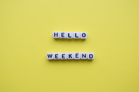 Hello Weekend word made of white square letter tiles on yellow background.の写真素材