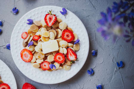 Pancake cereal, trendy food. Mini cereal pancakes with butter, honey, and strawberries.の写真素材