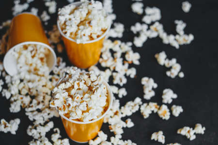 Salted popcorn in orange paper cups, on black backgroundの写真素材