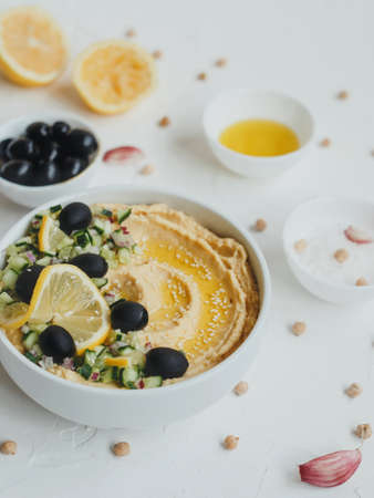 Hummus with olive oil, olives, lemon, garlic, sesame seeds, onions and cucumbers.の写真素材