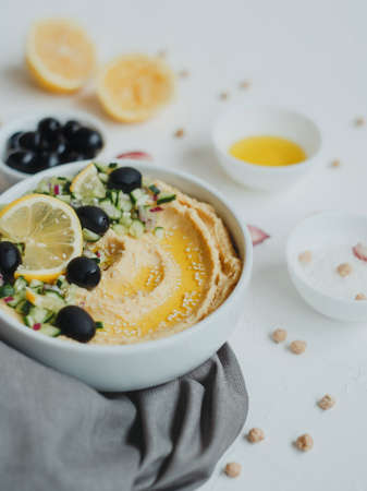 Hummus with olive oil, olives, lemon, garlic, sesame seeds, onions and cucumbers.の写真素材