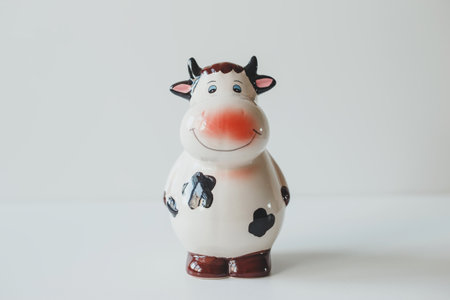 Cute ceramic figurine of a cow, on a light background, piggy bankの写真素材