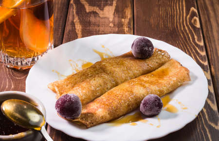 fried, Russian pancakes with honey and frozen cherries, and fruit tea on a blue background, side view, close-upの写真素材