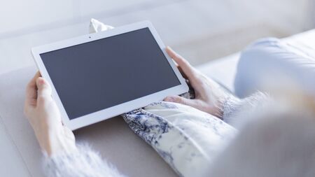 Woman at home relaxing reading on the tablet computerの写真素材