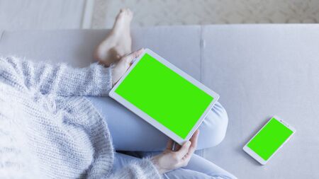 Woman at home relaxing reading on the tablet computer with pre-keyed green screenの写真素材