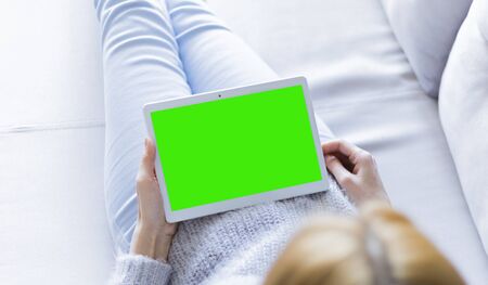 Woman at home relaxing reading on the tablet computer with pre-keyed green screenの写真素材