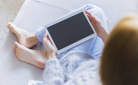 Woman at home relaxing reading on the tablet computerの写真素材