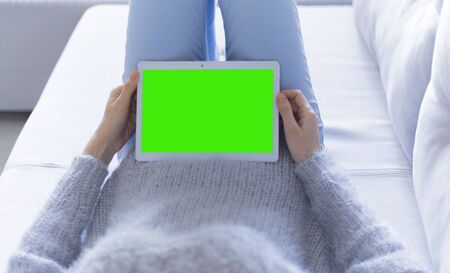 Woman at home relaxing reading on the tablet computerの写真素材