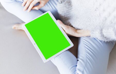 Woman at home relaxing reading on the tablet computer with pre-keyed green screenの写真素材