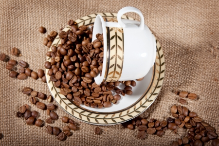 a cup wit coffee beans on the sackの写真素材