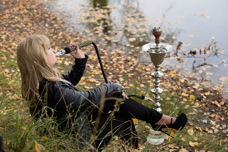 sexy blonde with big breasts smokes a hookah on the nature of the lakeの写真素材