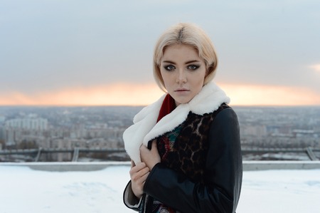 cute Girl in a brown sheepskin coat posing near a frozen lakeの写真素材