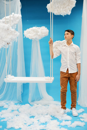 boy in white shirt swinging on a swing in heaven. angel Paradise