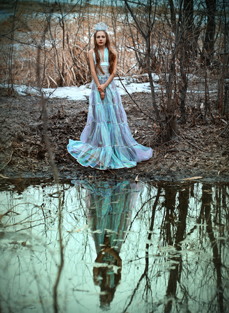girl in a blue dress posing in the woods near the lakeの写真素材
