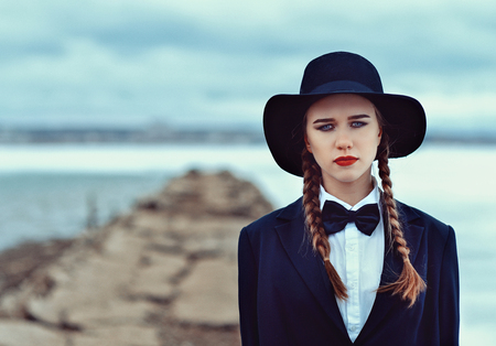 girl in hat walking on the bridge over an icy lakeの写真素材