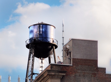 Water tower up high on west village New York City rooftop  One World Trade Center spire in background  の素材