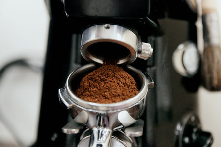 The process of automatic coffee grinding in a coffee grinder close-up. A handful of ground coffee in the holderの写真素材