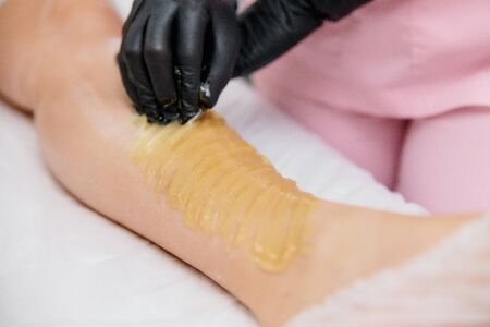 the procedure shugaring. master in black medical gloves to apply sugar paste with their own handsの写真素材