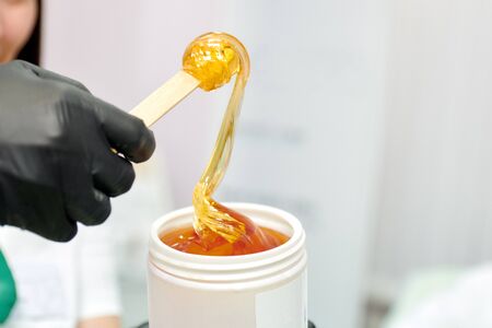 wrapping sugar paste for sugaring from a white jar on a wooden spatulaの写真素材