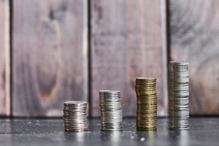 four stacks of coins on a wooden background in the form of an ascending graph	