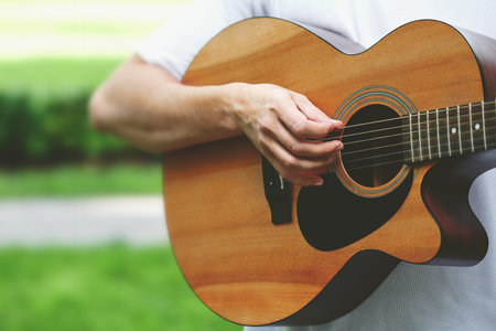 close-up of a brown classical acoustic guitar with a male musician's hand playing the strings....