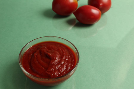 red tomato sauce in a saucepan in the background are vegetables red tomatoes on a green background...