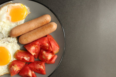 food Breakfast protein fried eggs fried eggs sausage and salad vegetables red tomatoes are on a gray...