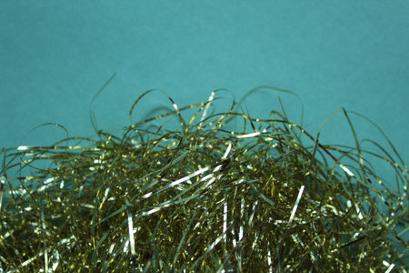 yellow Christmas tinsel and bows decorations for gifts on a green mint turquoise background with...