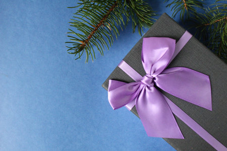 new year's Christmas background gift gift box with purple lilac fuchsia ribbon and bow on a blue...