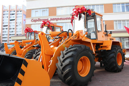big yellow orange tractor with bucket and big red bows on the roof