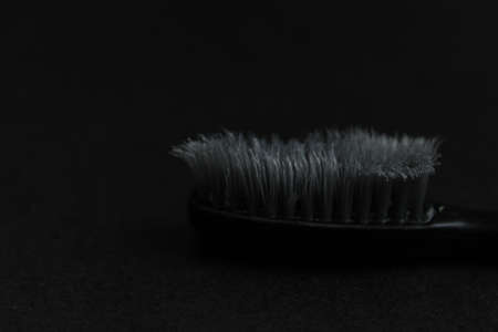 black gray used old battered toothbrush on a black background side view copy spaceの写真素材