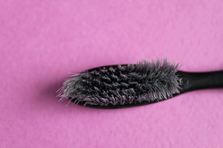 black gray old used toothbrush on fuchsia pink lilac bright background for girls side view of copy...