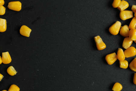 food background bright sugar yellow corn at the edges of the top right or from bottom to top on black background copy spaceの写真素材