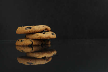 chocolate homemade holiday cookies with chocolate drops are stacked on top of each other with a reflection side view of copy spaceの写真素材