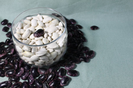 white beans in a glass jar and red blue on mint light background of a copy of the space.の写真素材