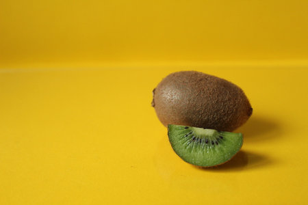 A trendy still life of a kiwi and a piece of fruit lie on the Illuminatiited yellow background with a place for the text of the copyspace.の写真素材