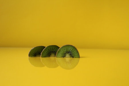 Three slices of kiwi halves lie in a row on trend iluminaited yellow with a copy of the space place for text.の写真素材