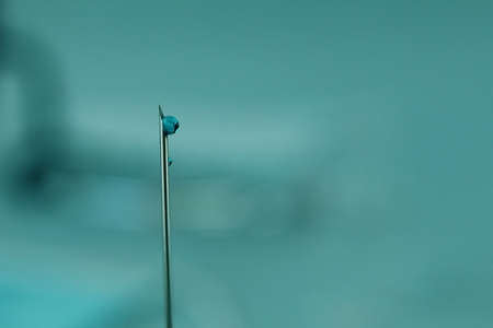 vaccination drop blood medication on a needle on a blue blue background with a copyspace.の写真素材