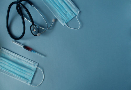 Flatlay medicine background syringe mask stethoscope lie on a blue background with a place for text with a copyspace view from above.の写真素材